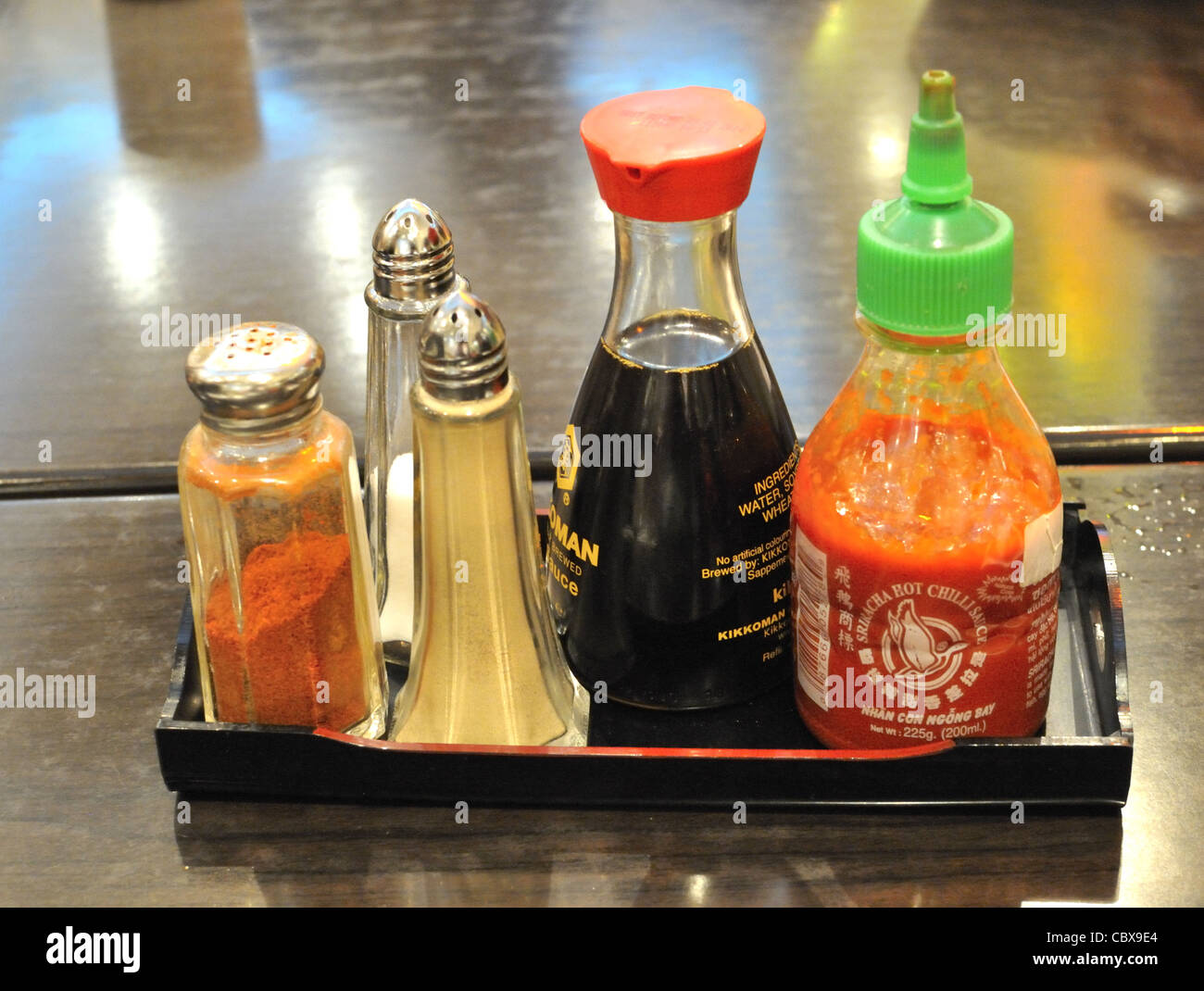 Chinese restaurant condiments of soya sauce, chiily sauce, salt and pepper. Stock Photo