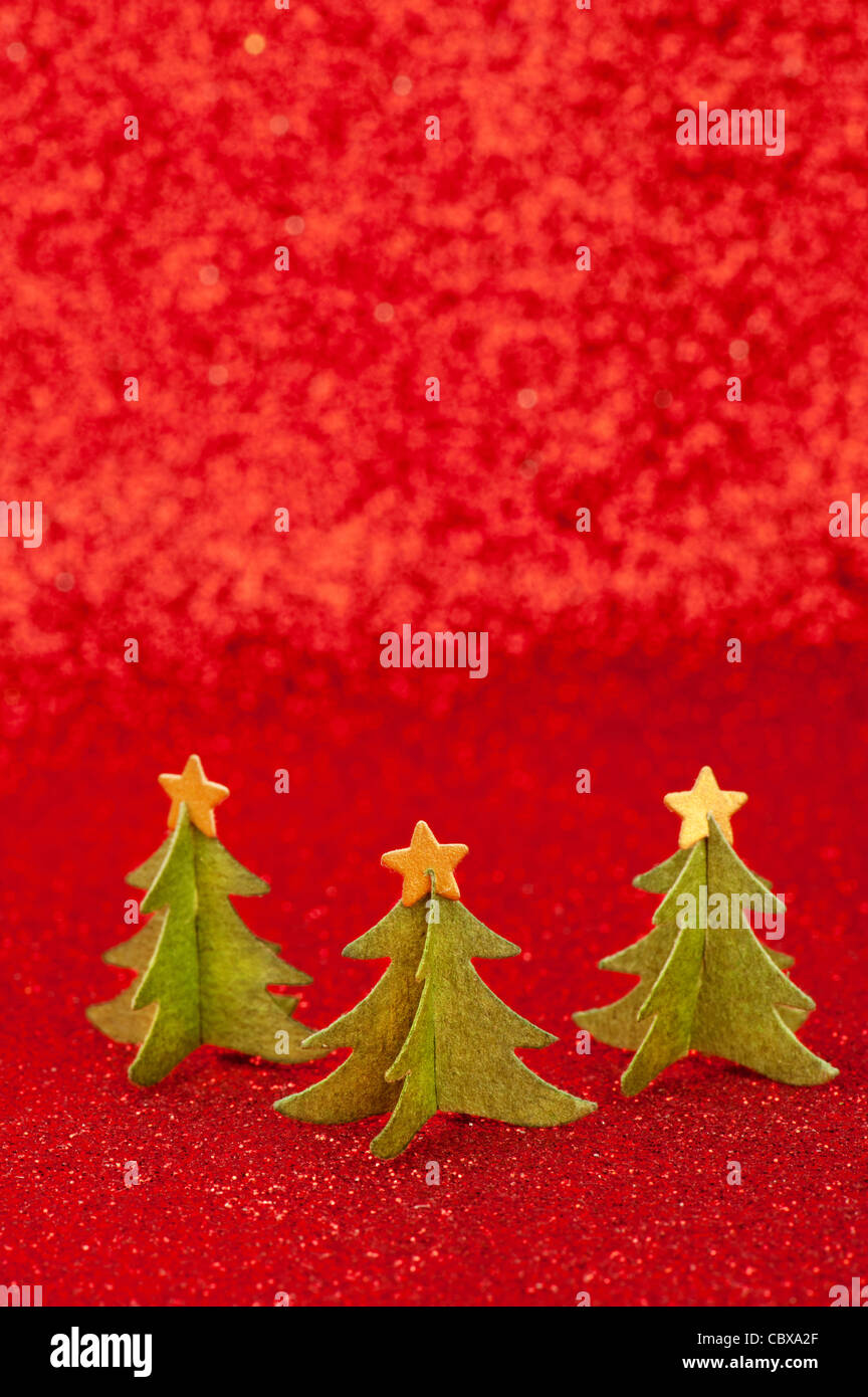 Three green paper Christmas trees with golden stars on tops, over red ...