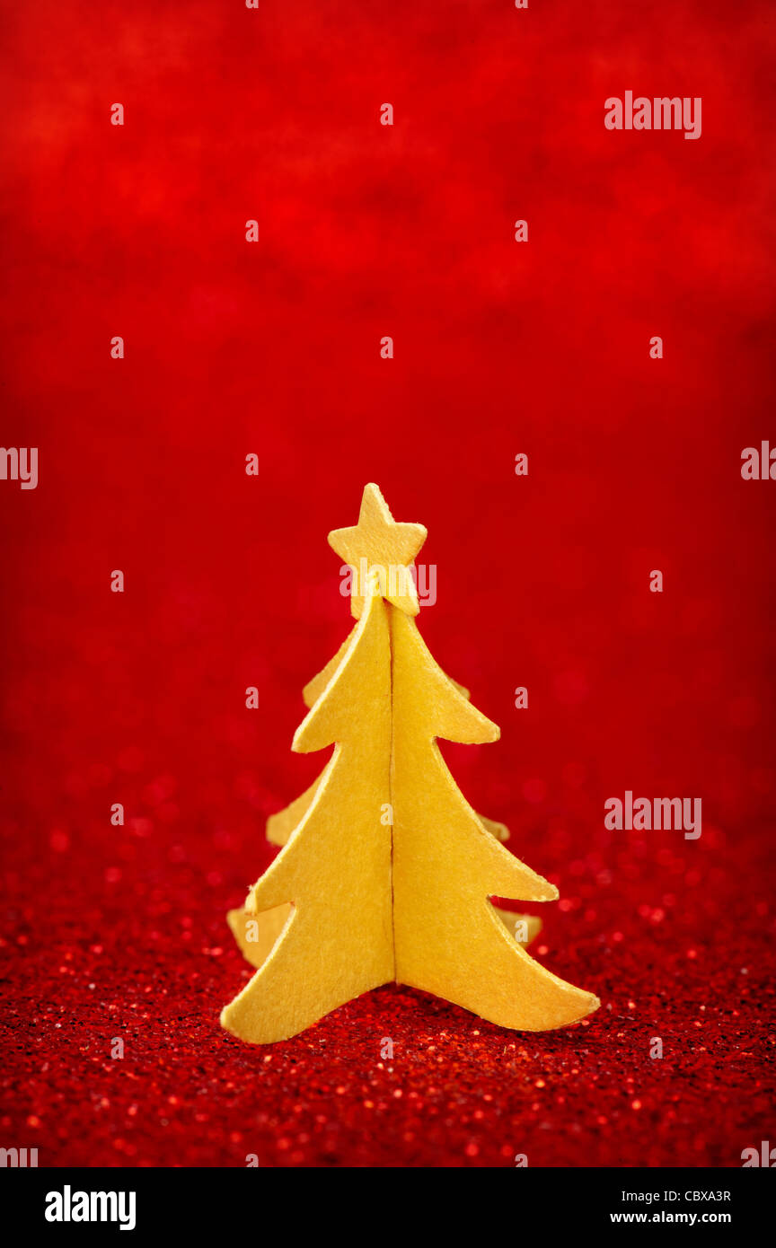 Golden paper Christmas tree with star on top, over red glitter ...