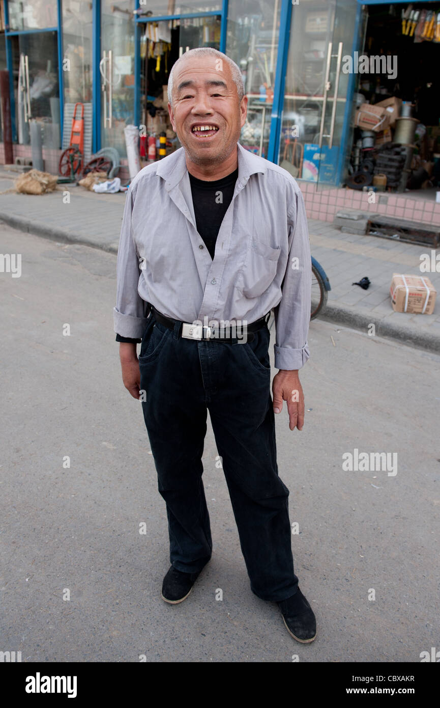 Mr. Li BaoTian works as a night guard,  guarding metal building materials for electricity poles Stock Photo