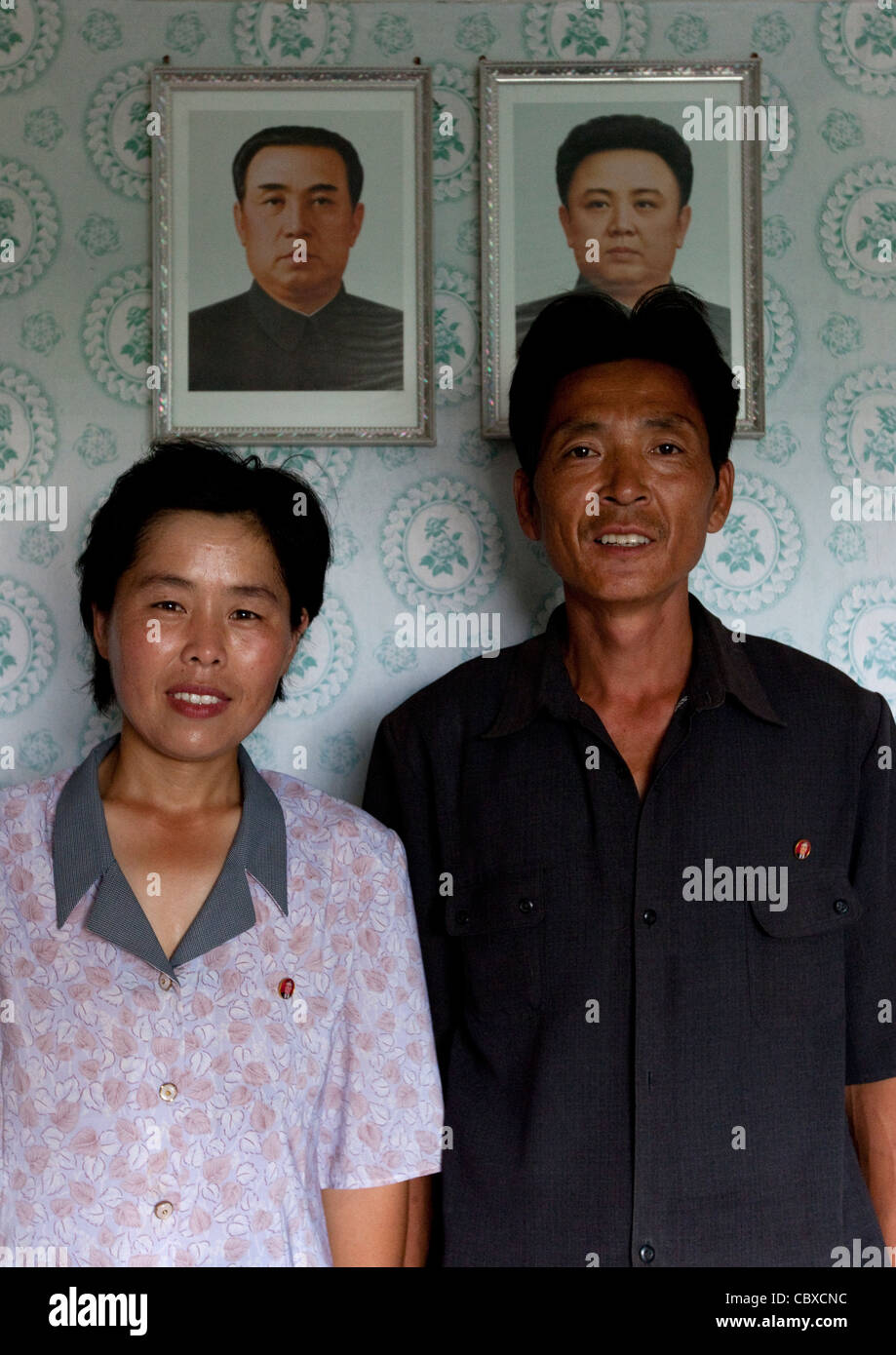 NORTH KOREAN COUPLE IN FRONT OF PORTRAITS OF THE LEADERS IN THEIR HOUSE, NORTH KOREA Stock Photo