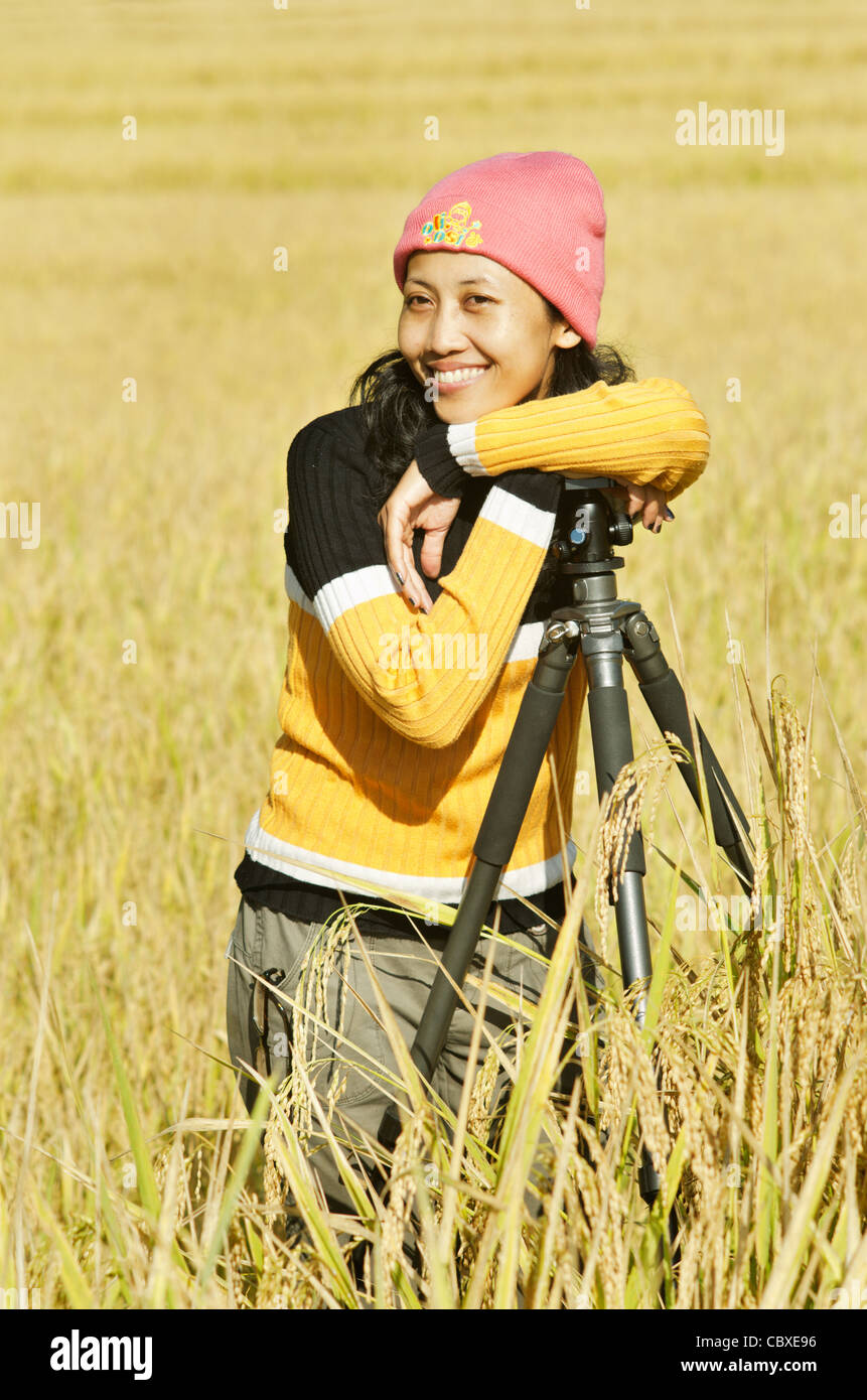 Woman leaning on a tripod, standing in a rice field ready for harvest, Thailand, Asia Stock Photo