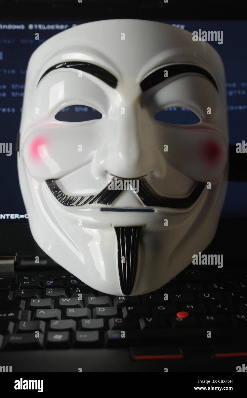 Mask used by the hacker group 'Anonymous' lying on a computer keyboard Stock Photo