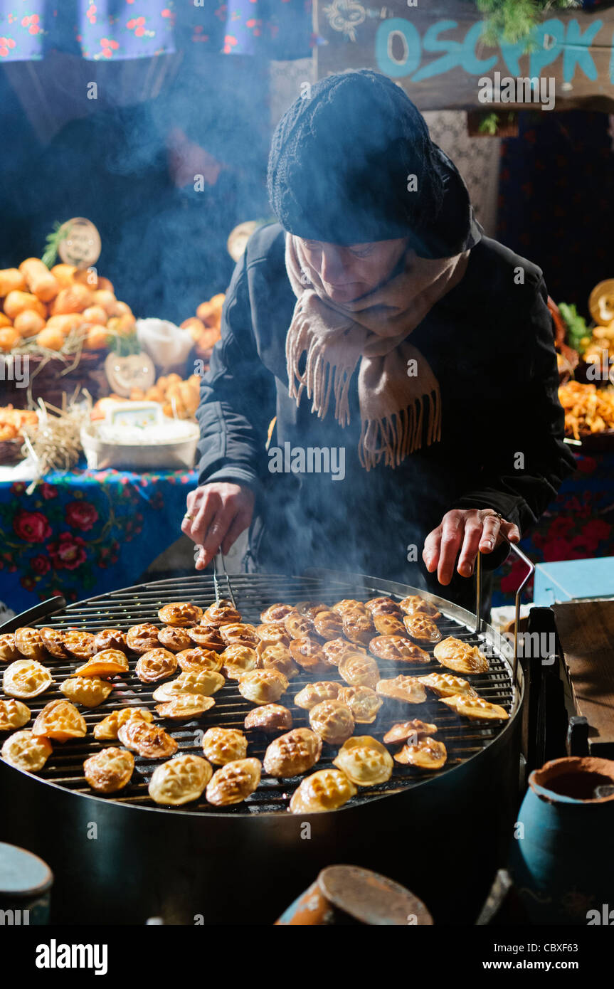 Woman cooking Oscypki, a traditional Polish smoked sheep milk cheese, barbequed and served with cranberry sauce Stock Photo