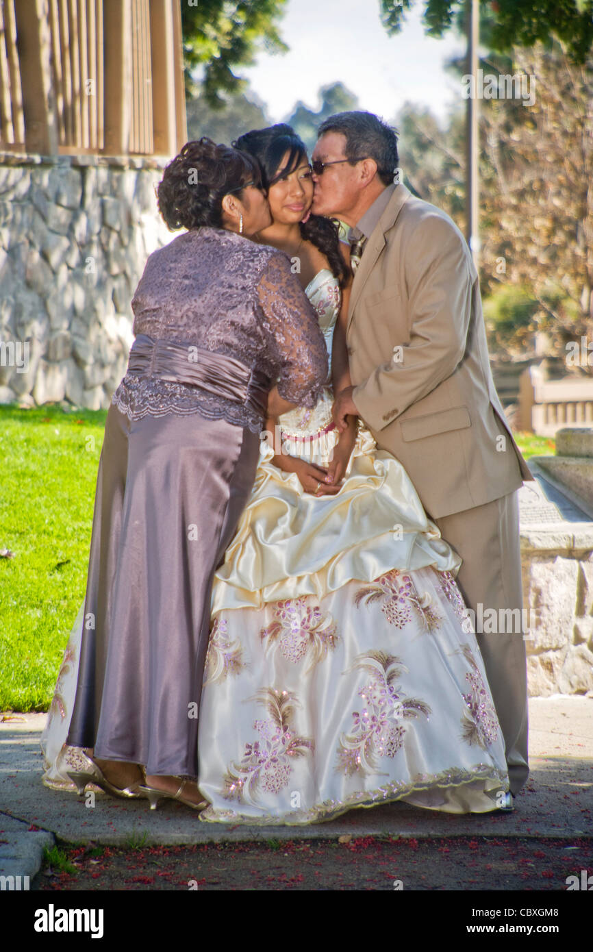 Parents in Cerritos, CA, kiss their formally-dressed daughter at her quinceanera, a common rite of passage for fifteen-year-old Stock Photo