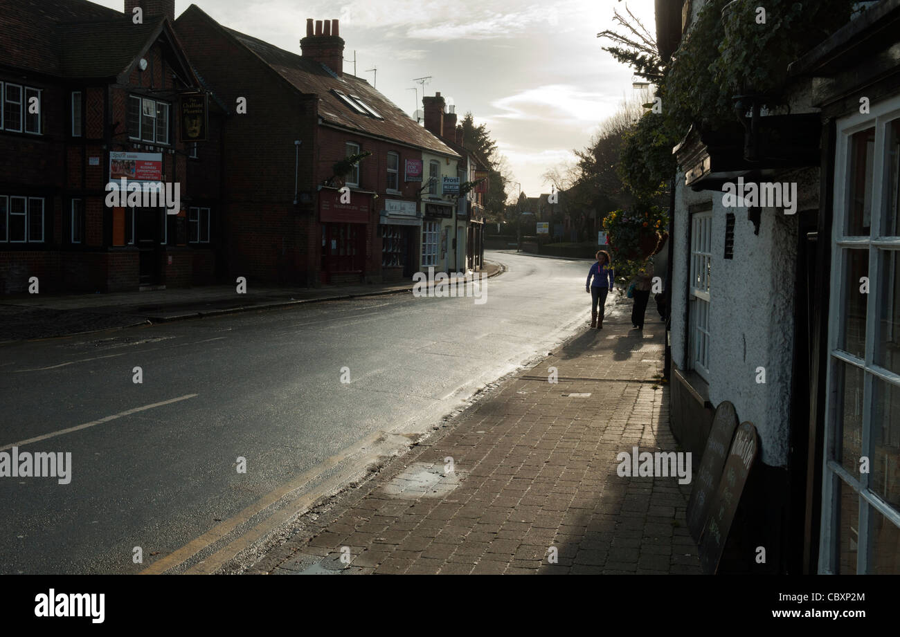 Two people walking along a pavement in an otherwise empty high street