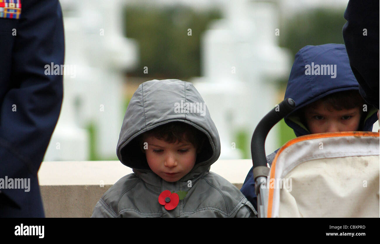 A young boy wearing a poppy bows his head in respect at a remembrance day parade. Stock Photo