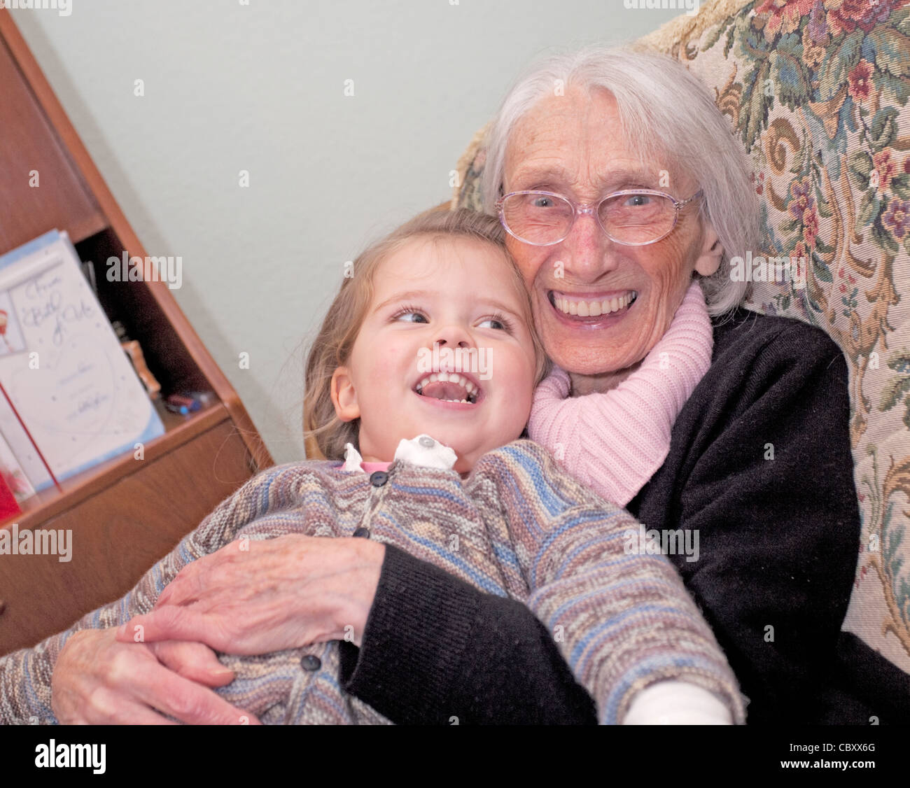 great grandmother sat having hugs with her great grand daughter Stock Photo