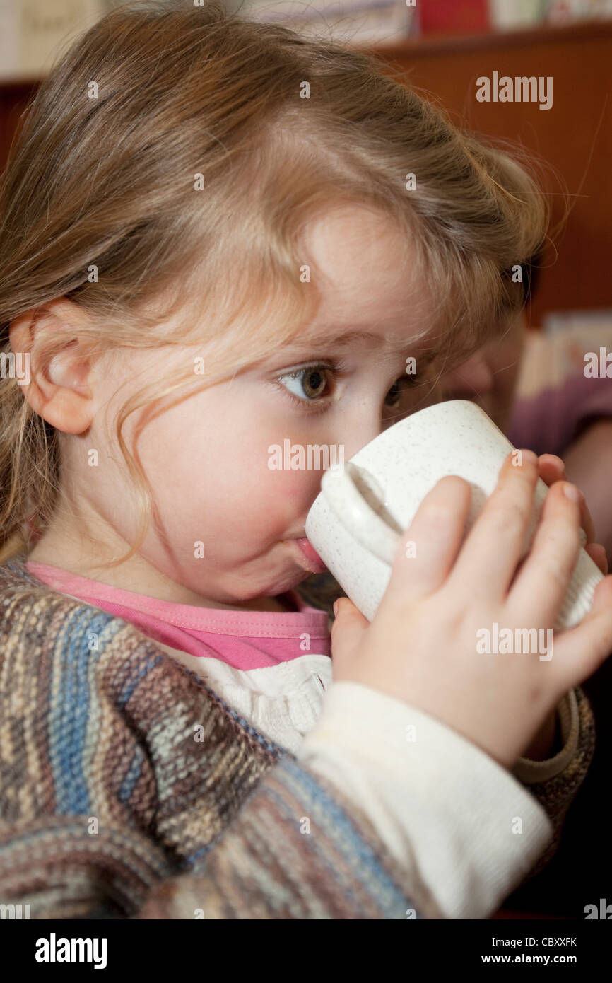female toddler drinking out of a china mug Stock Photo
