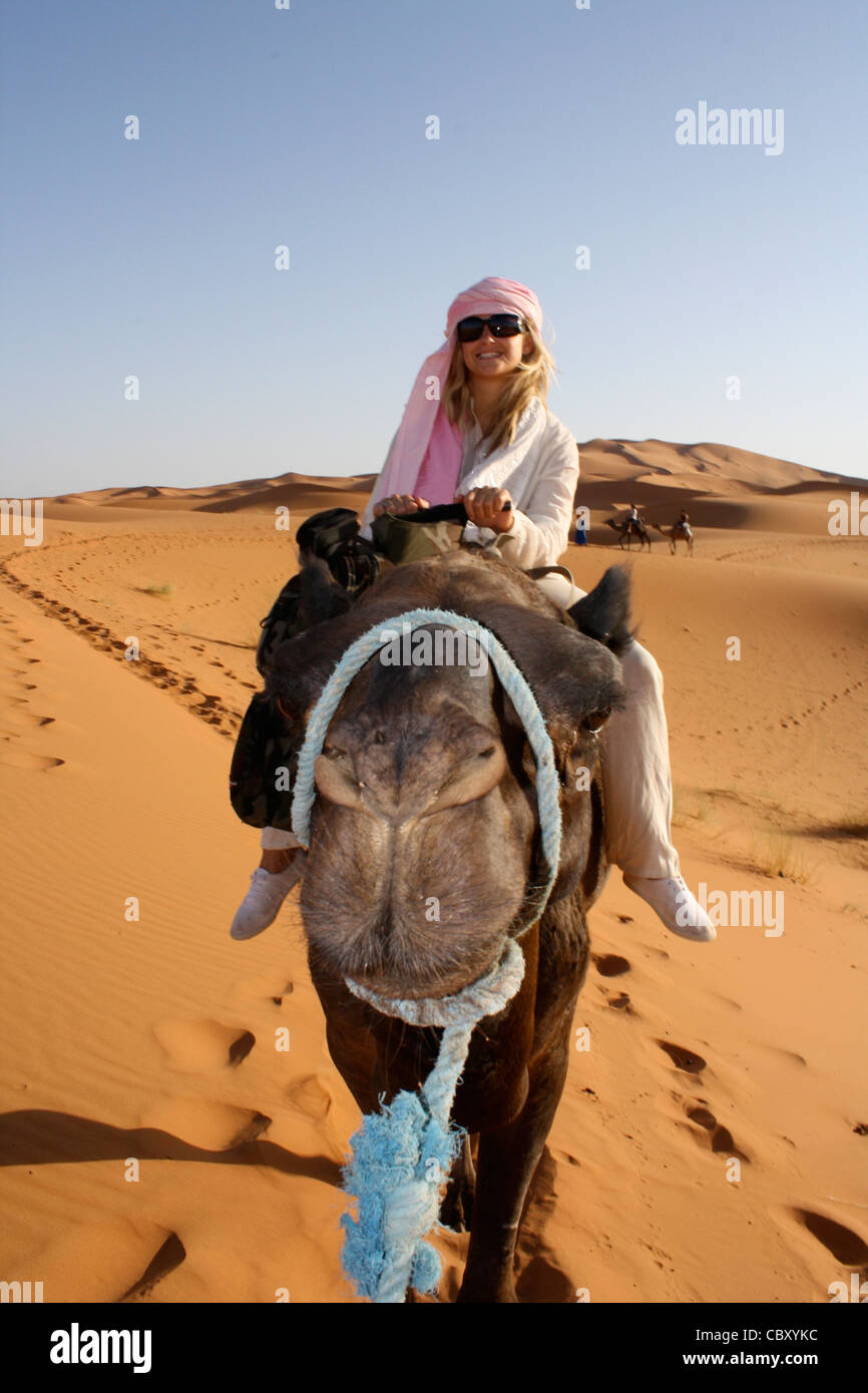 A woman riding a camel in Erg Chebbi, Sahara, Morocco Stock Photo