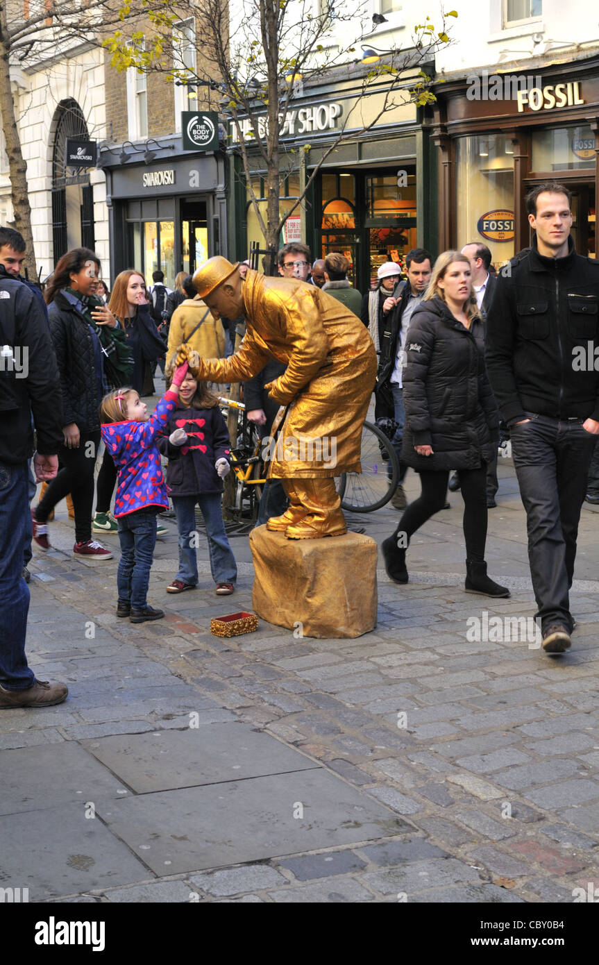 Living statue street performer accepting a gift from a little girl