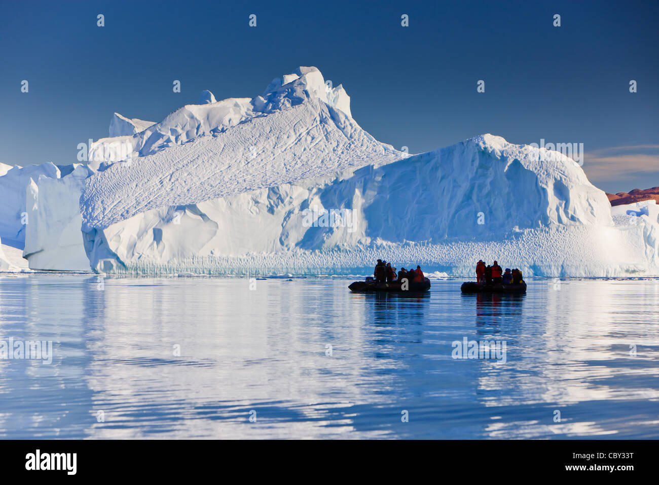 Cruising between the icebergs at Røde Ø, Scoresbysund, Greenland Stock Photo