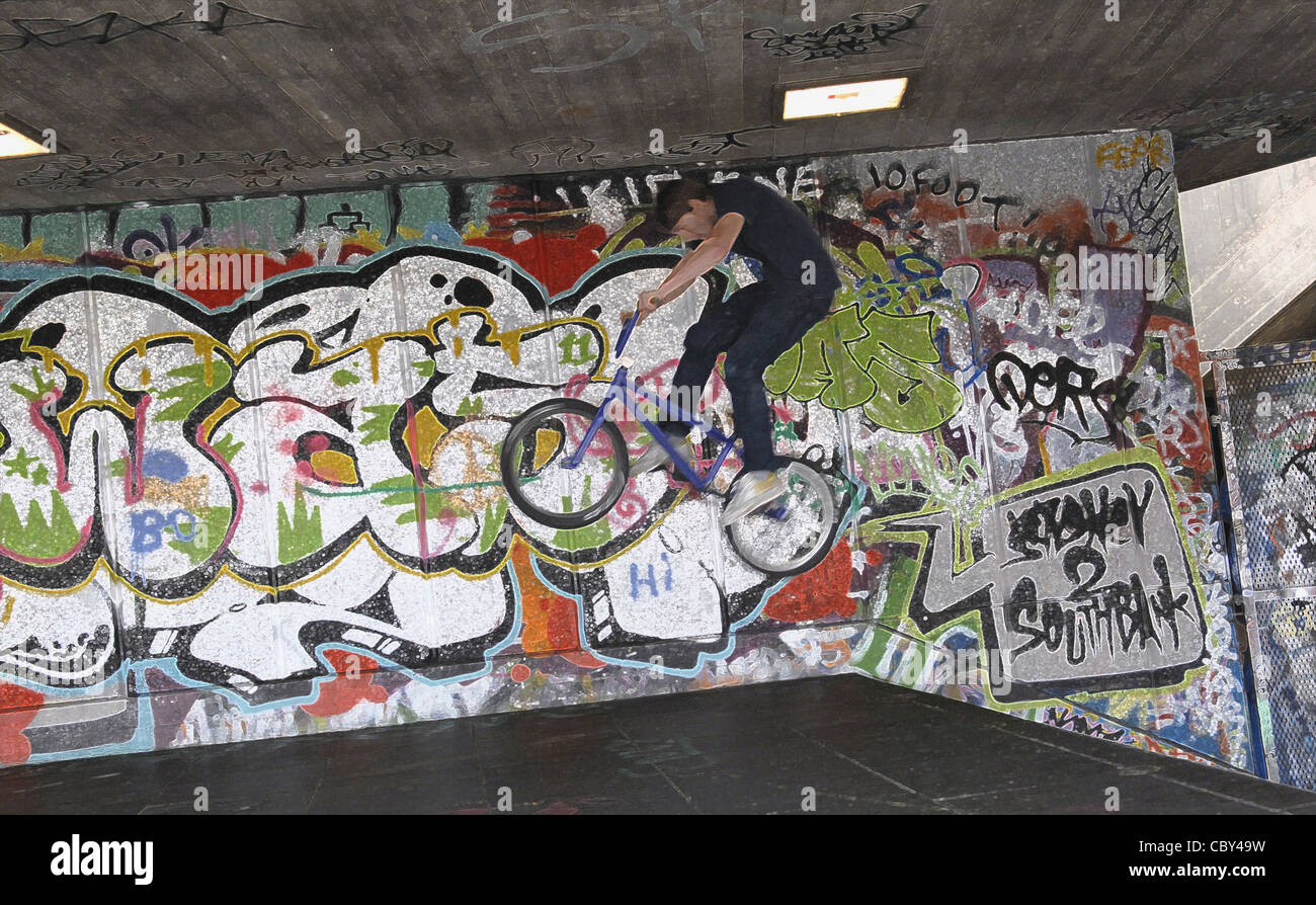 BMX rider pulling tricks in front of graffiti wall in London. The image has been treated in Photoshop to give a graphic feel. Stock Photo