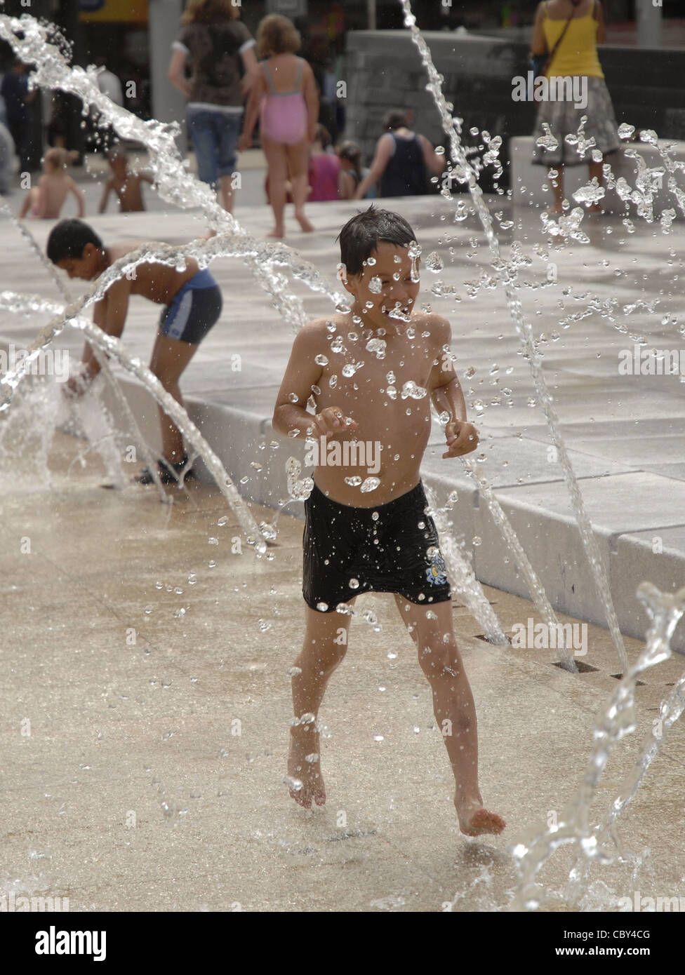 Children playing in water fountains during a hot day in Nottingham, UK. These fun water jets are situated in City Square. Stock Photo
