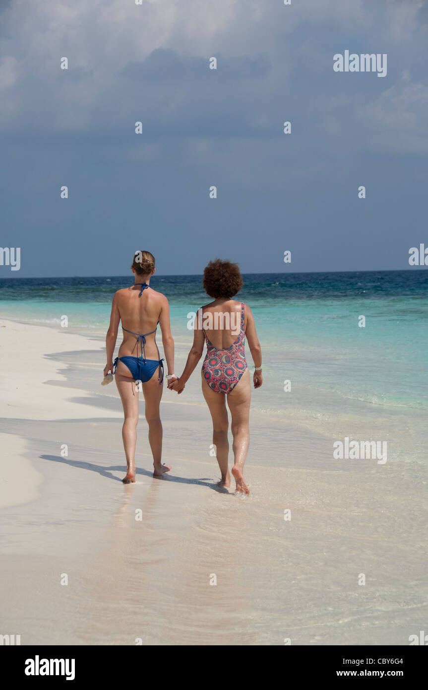 Maldives, North Male Atoll, Island of Kuda Bandos. Gay women holding hands on beach. Stock Photo