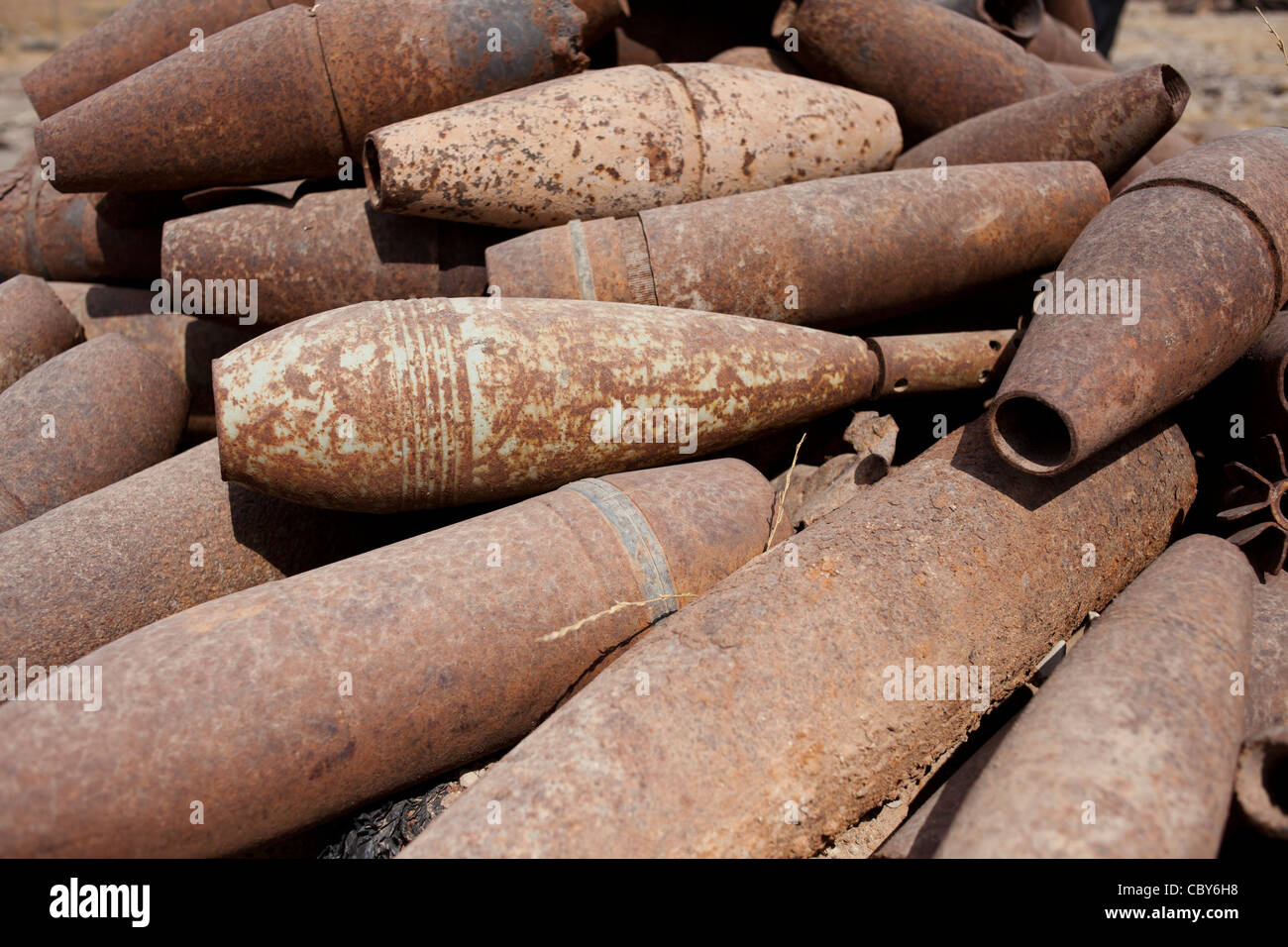 Artillery and mortar shells lie rusting in the sun in a scrap yard in Iraq. Stock Photo