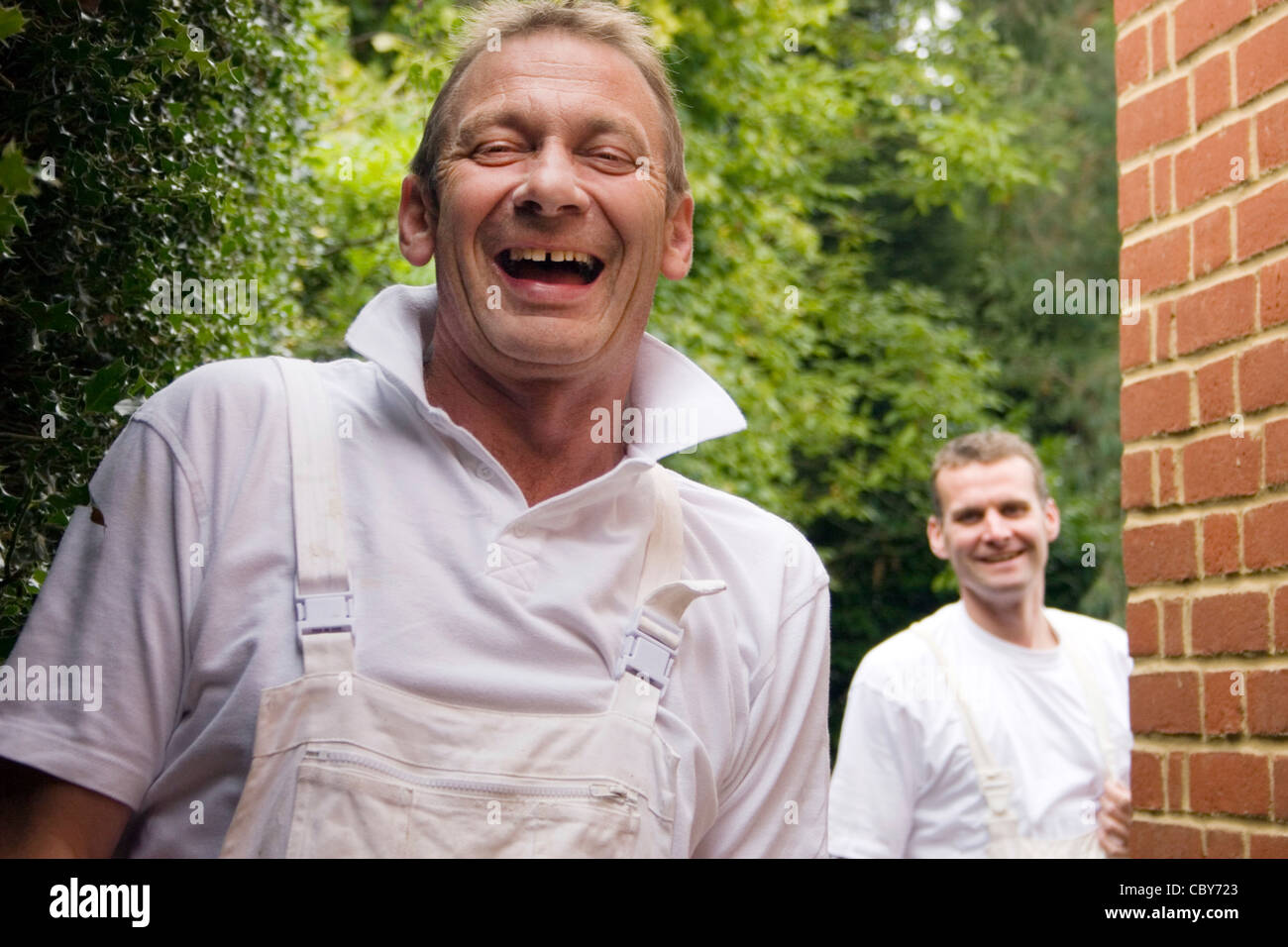 portrait two happy labourers wearing overalls to paint and decorate property Stock Photo