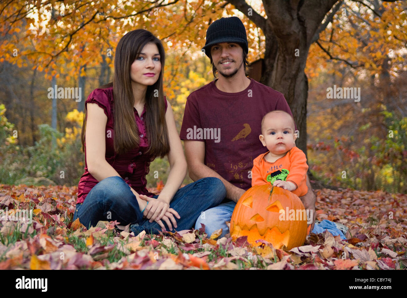 Young Family Posing With Jack-O-Lantern on Lawn Stock Photo