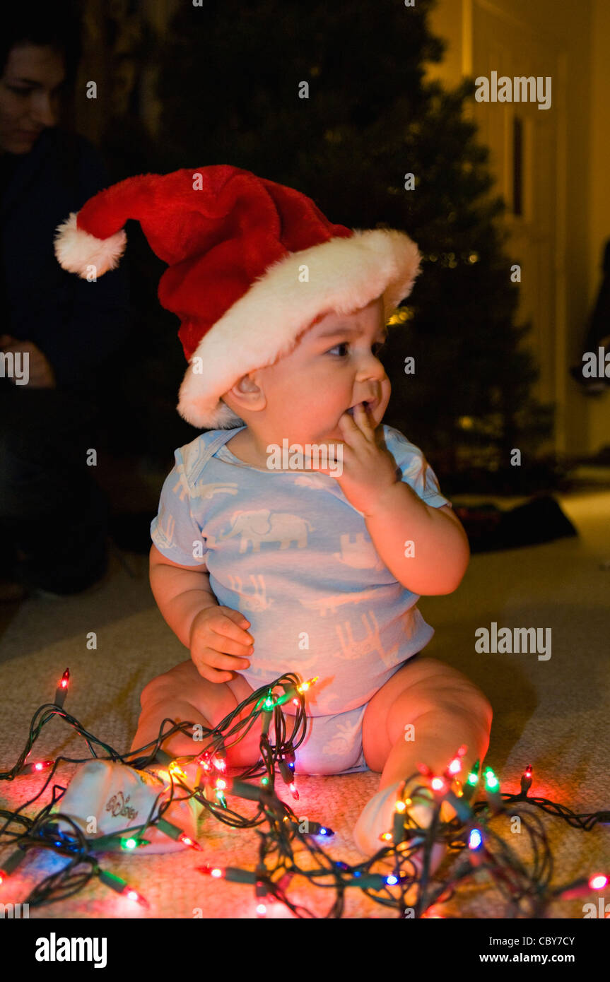 Seven Month Old Baby Boy with Christmas Lights and Wearing Santa Hat Stock Photo