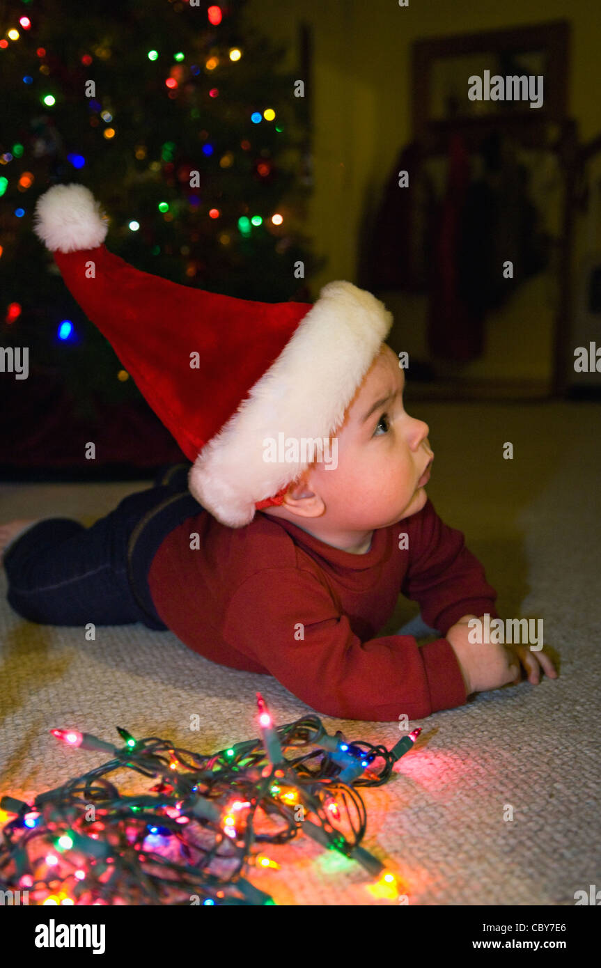 Seven Month Old Baby Boy with Christmas Lights and Wearing Santa Hat Stock Photo