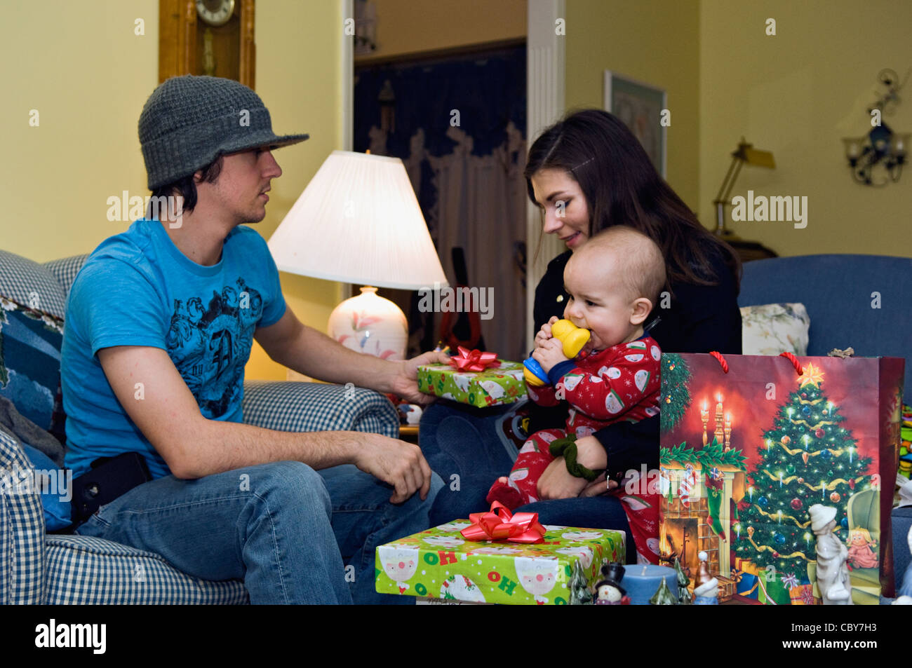 Young Couple with Baby Boy Exchanging Christmas Gifts Stock Photo
