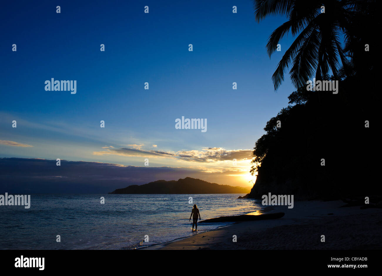 Woman walking at beach in Costa Rica at sunset with palm trees Stock Photo