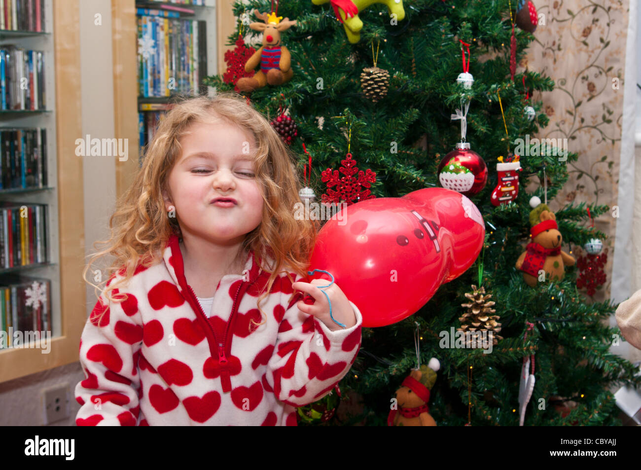 3 Year Old Child Girl Infant Toddler Standing In Front Of A Xmas Christmas Tree Pulling A Funny Face Stock Photo