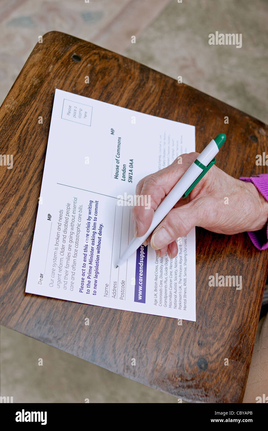 Elderly woman writing to MP to campaign for a better system & rights for older & disabled people Stock Photo