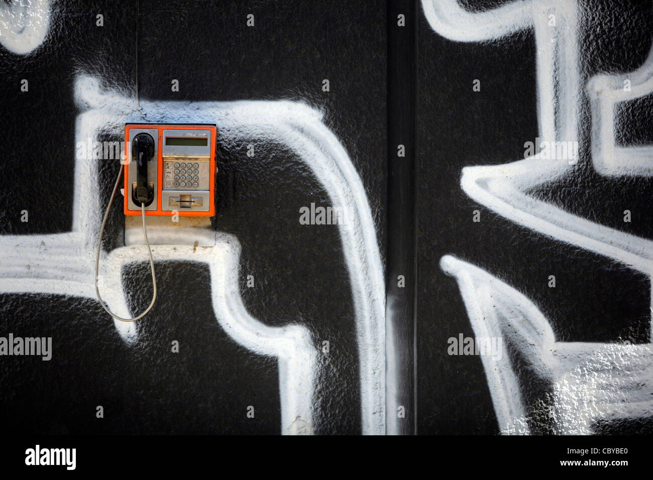 Orange public telephone on a graffiti wall Stock Photo