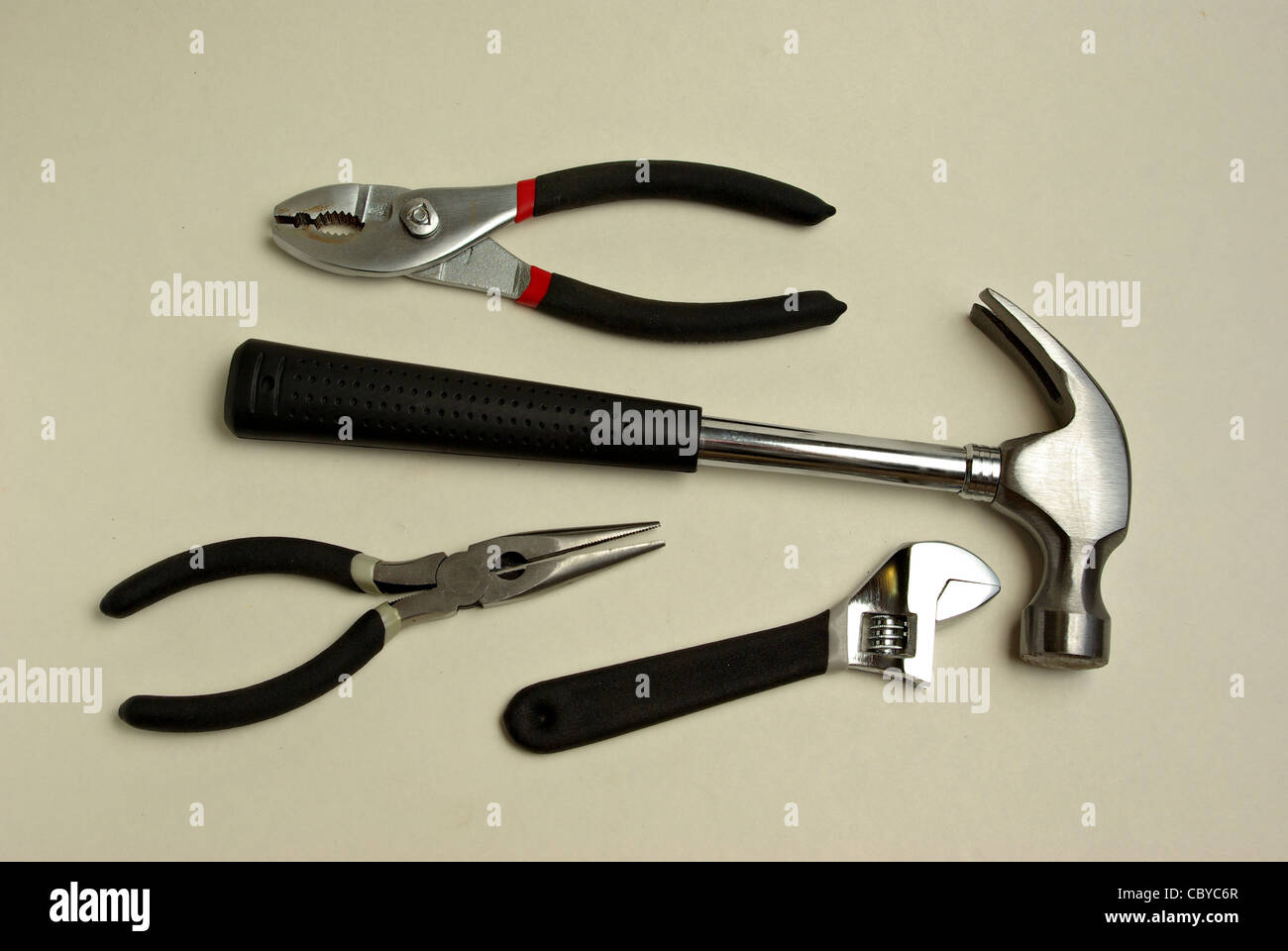 A hammer, needle nose pliers, pliers, adjustable wrench all sit on a white background. Stock Photo