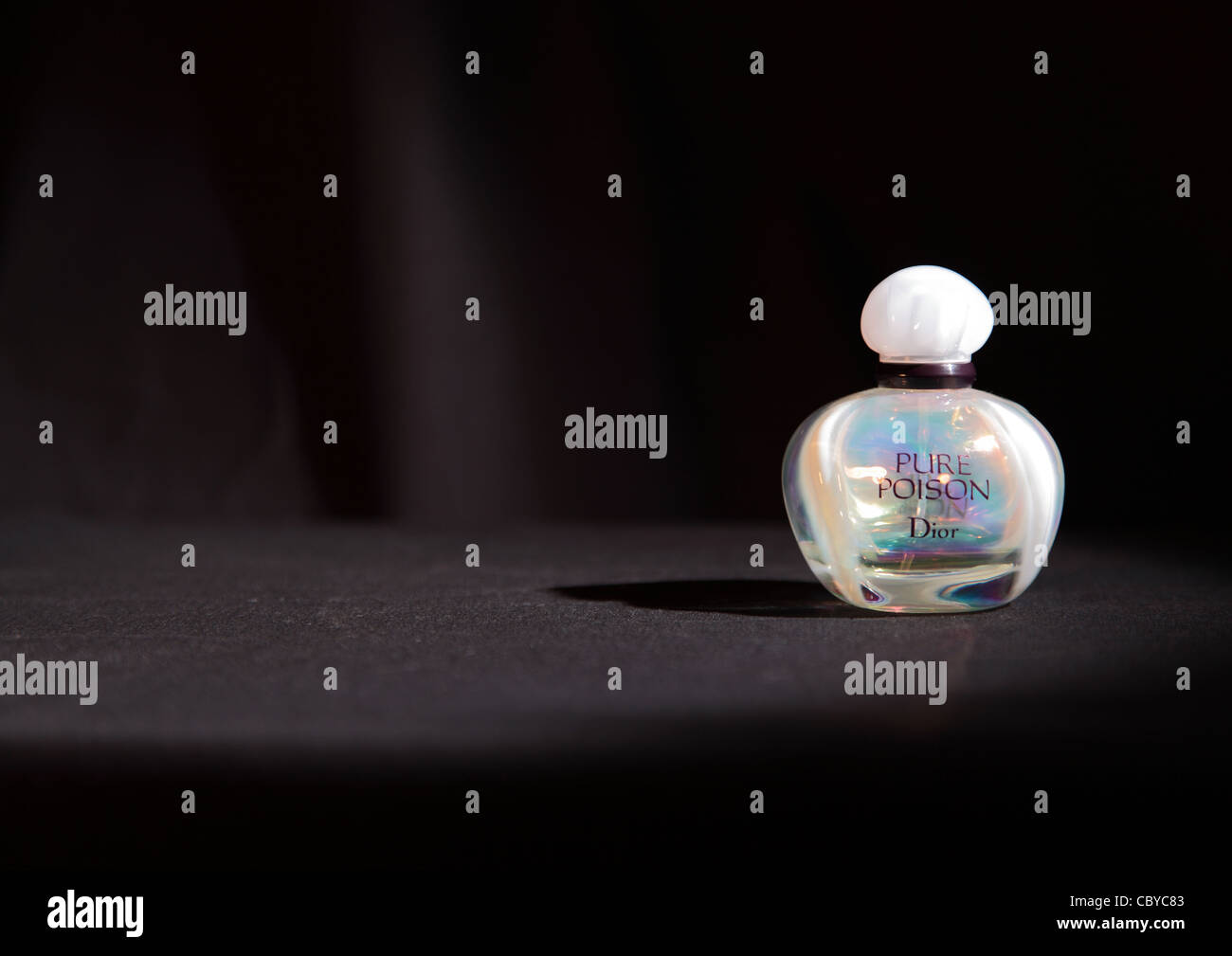 Bottle of Dior Pure Poison perfume spotlit on black background Stock Photo