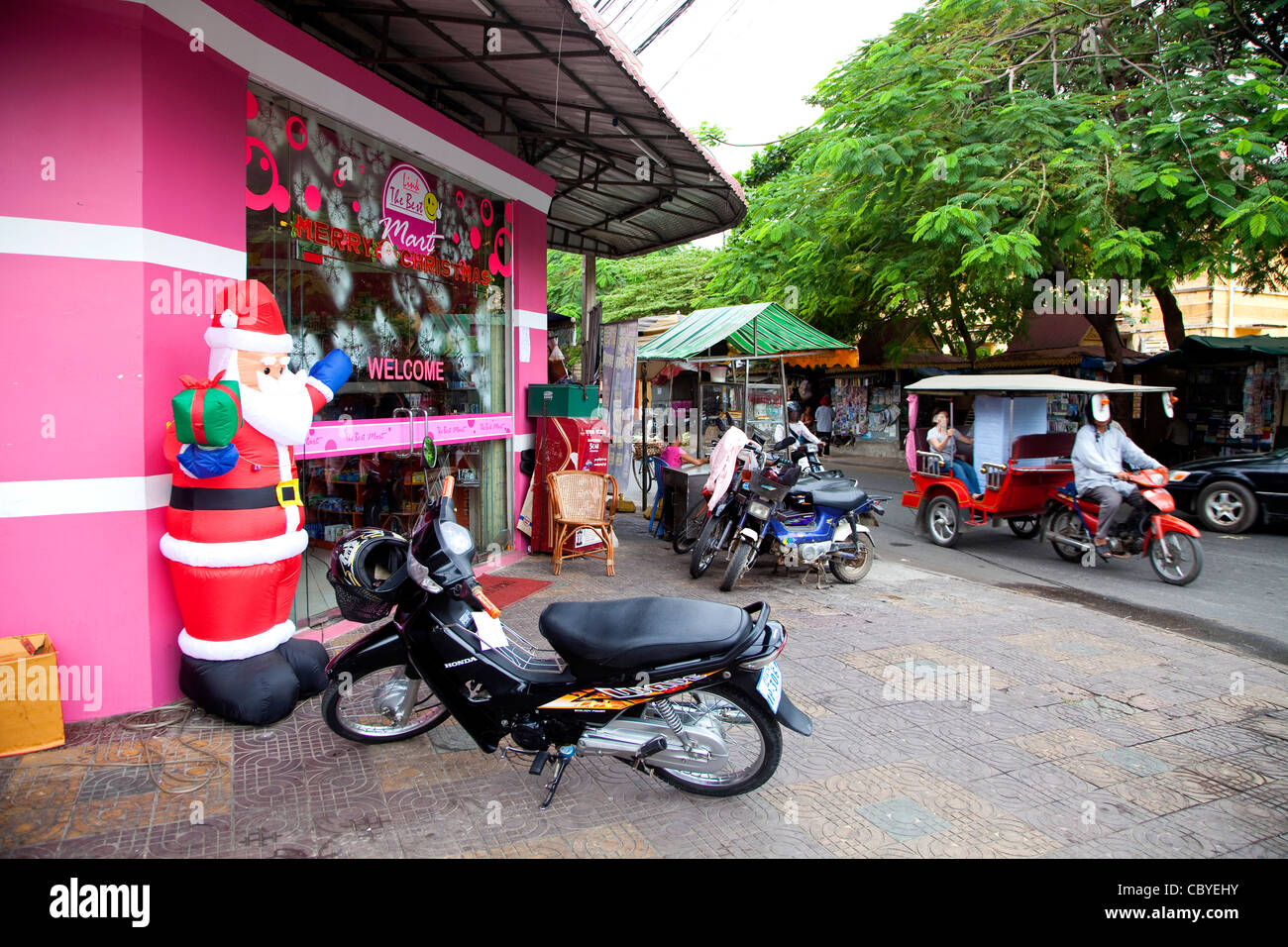 Traffic with cars, SUVs, bikes, scooters and bicycles in Phnom Penh, Cambodia, Asia. Santa Claus and Christmas shop with Xmas decorations Stock Photo