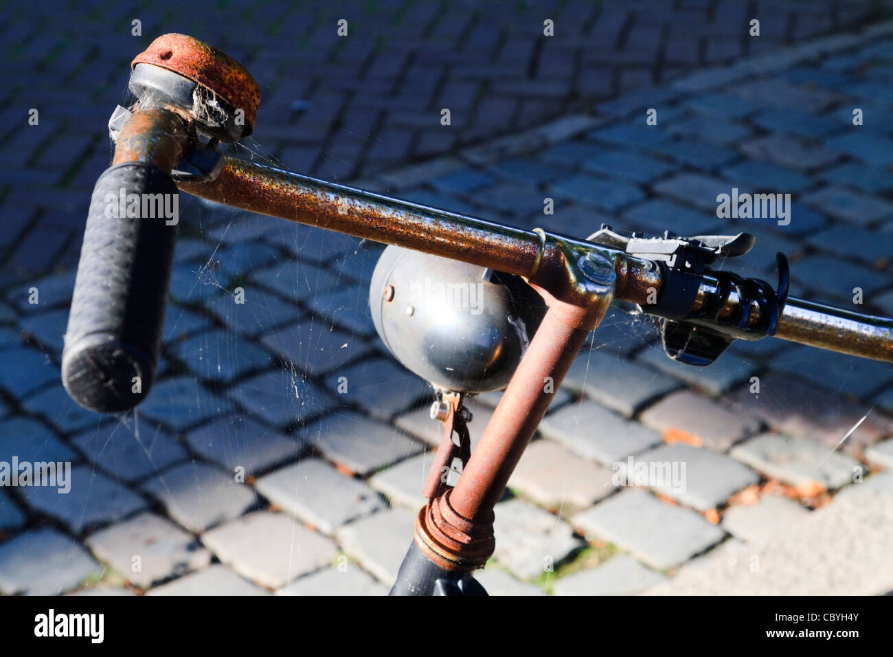 An old rusty dumped bicycle on a cobbled street Stock Photo