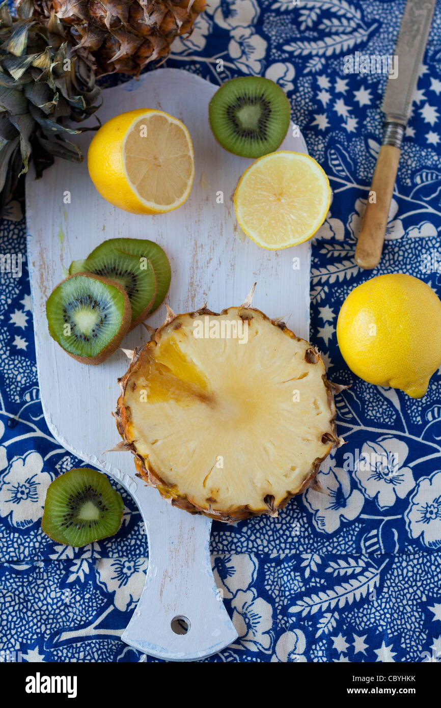 Lemons, kiwi and a pineapple on a chopping board Stock Photo