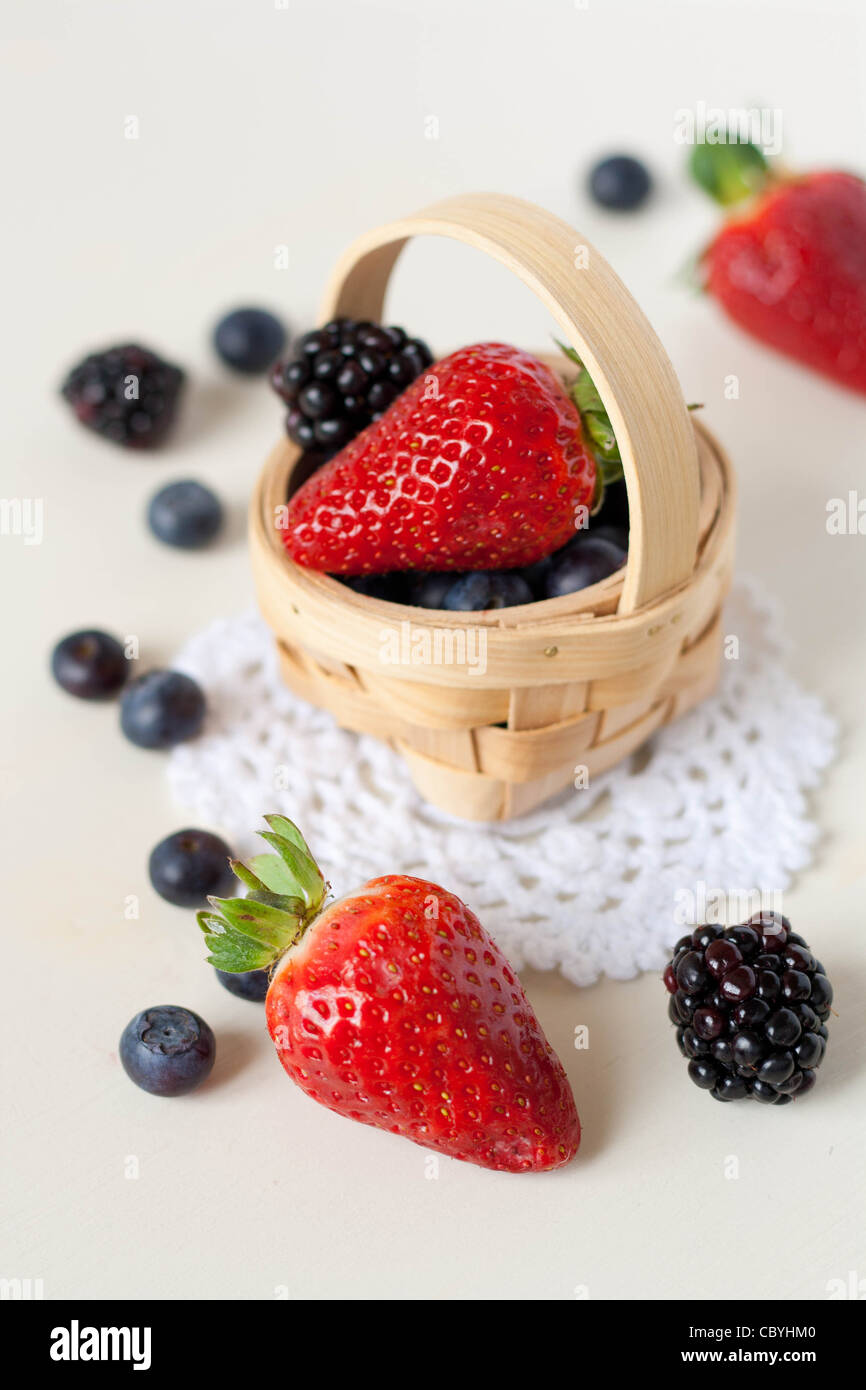 Strawberries, blackberries and blueberries in a basket on a crochet doily Stock Photo