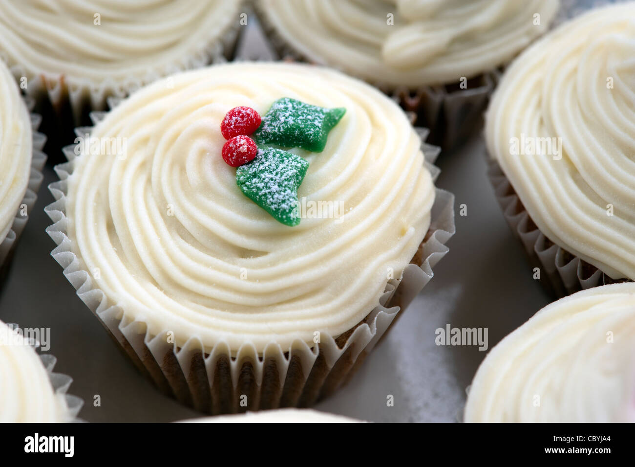 Cup cake with white icing and christmas holly decoration Stock Photo