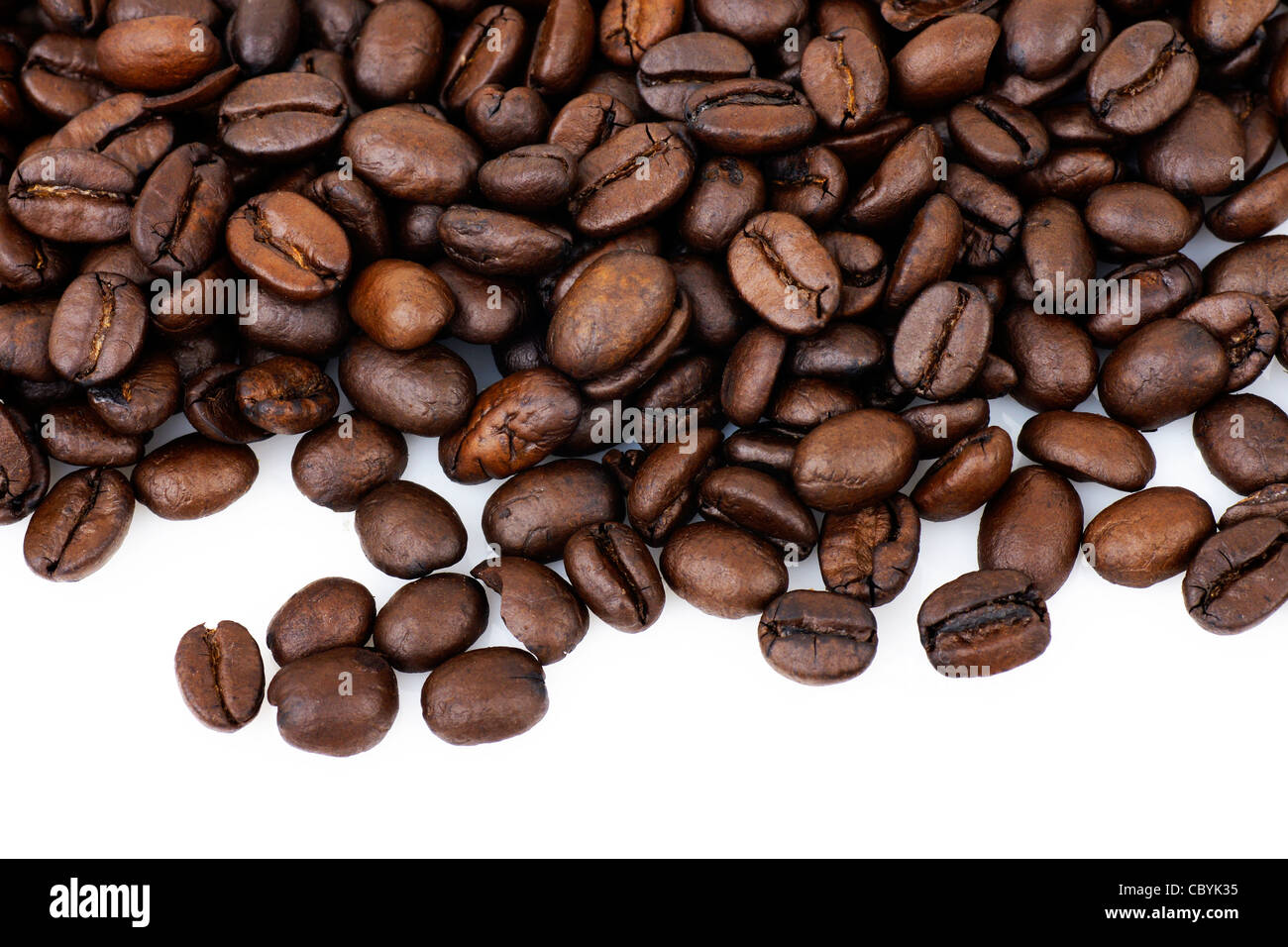 Beautiful macro of dark roast coffee beans over white background with copy space. Stock Photo