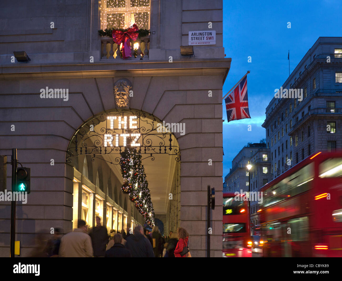 The Ritz Hotel at Christmas with Union Jack flag shoppers and passing red buses Piccadilly London Stock Photo