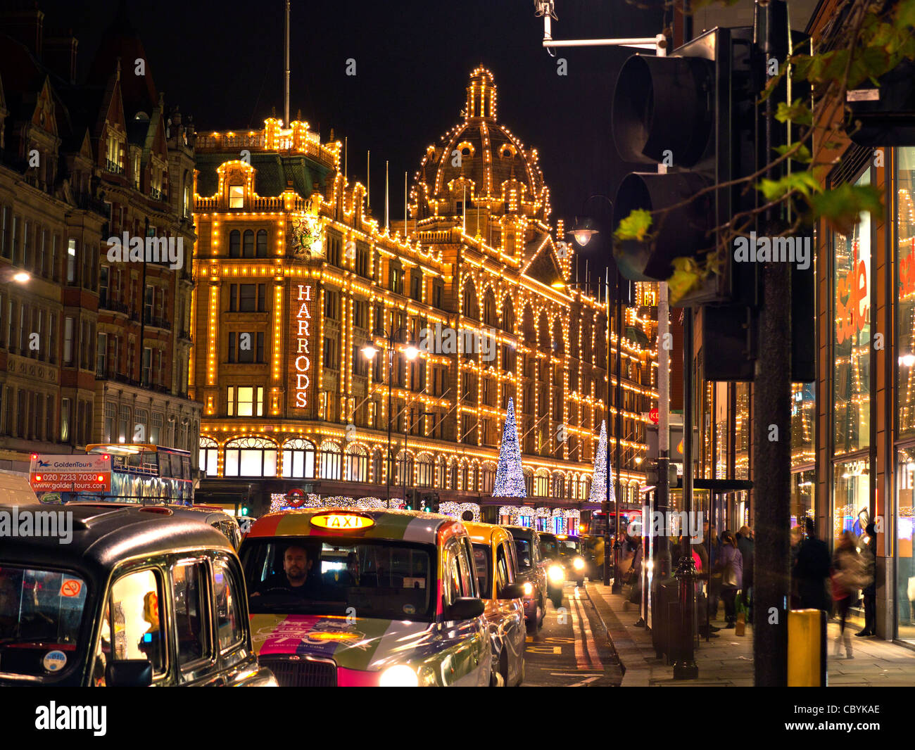 Harrods Department Store with Christmas lights at dusk with taxi cabs waiting in line.Knightsbridge London England UK Stock Photo