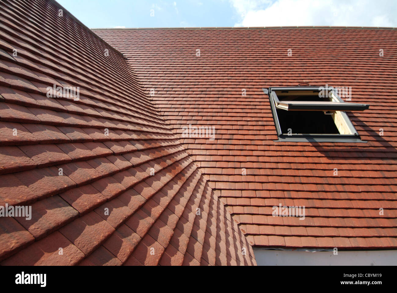 New roof tiling on a refurbished detached house including Velux type window Essex England UK Stock Photo
