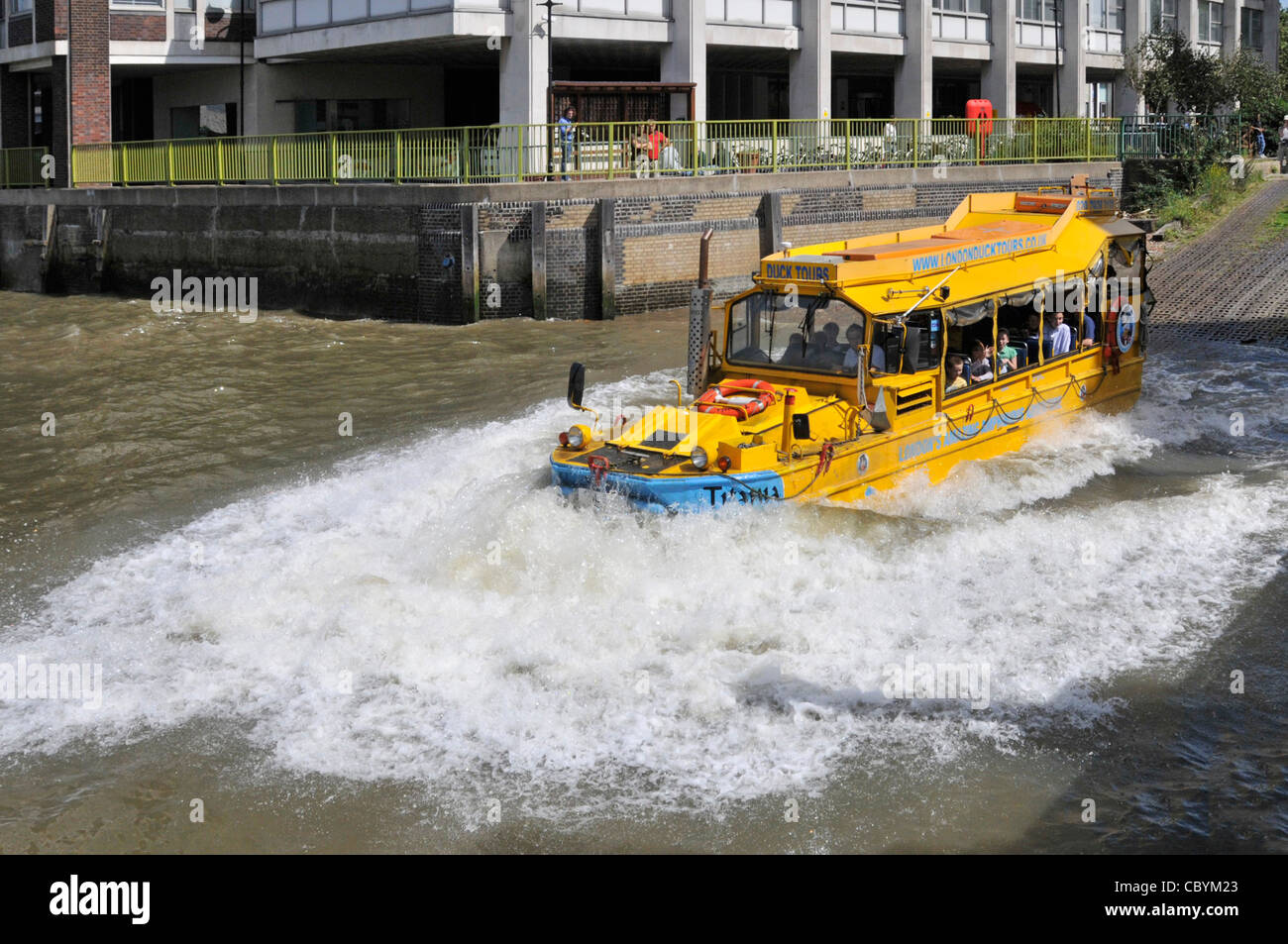 London tourism business amphibious Duck Tours makes big water splash entry into River Thames for tourist people on sightseeing tour in yellow boat UK Stock Photo