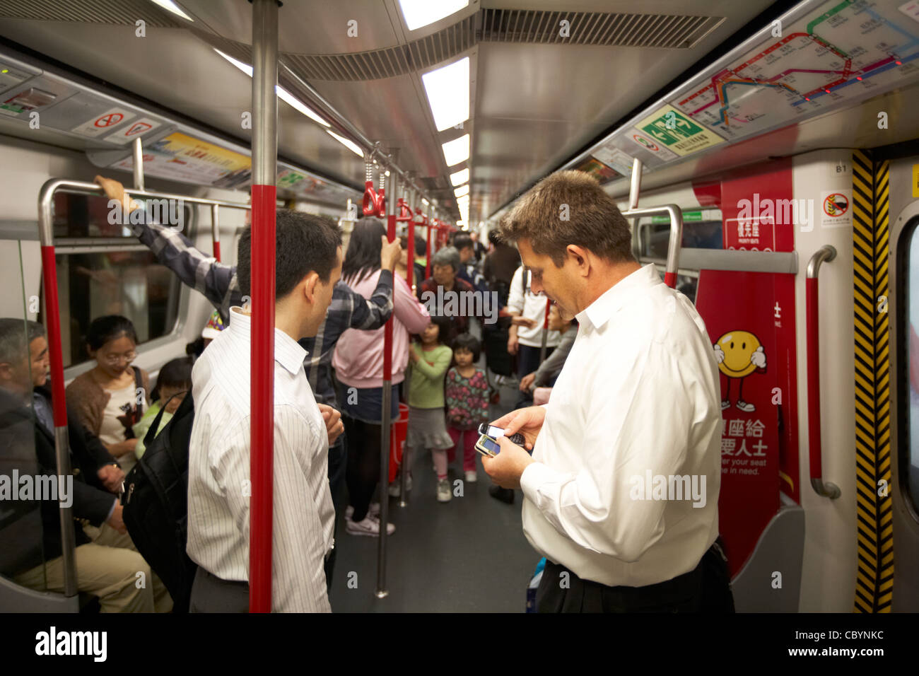 western businessmen with mobile phones inside train carriage on hong kong mtr public transport system hksar china asia Stock Photo