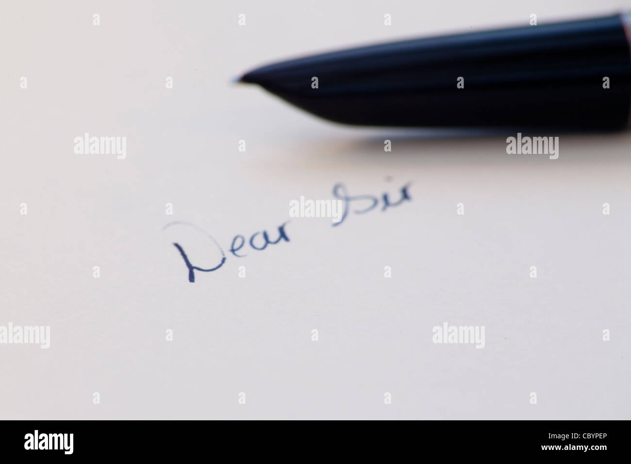 the words 'Dear Sir' handwritten in ink with fountain pen in background Stock Photo