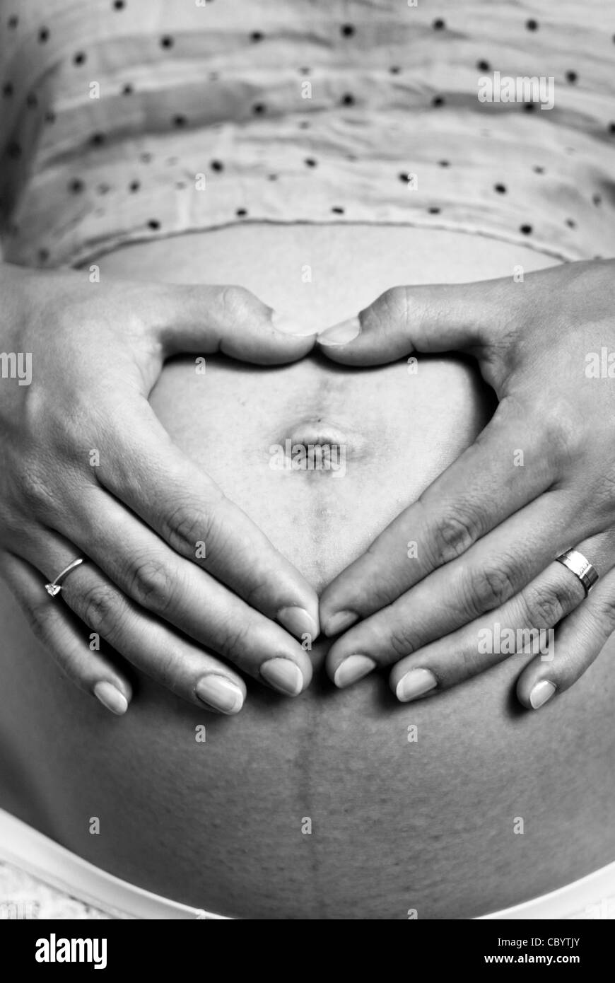 Pregnant woman holding hands on her unborn baby in the belly Stock Photo