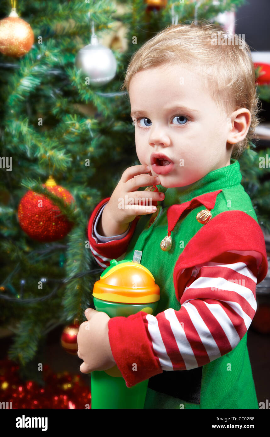 One year old baby boy by the Christmas tree, dressed as an elf Stock
