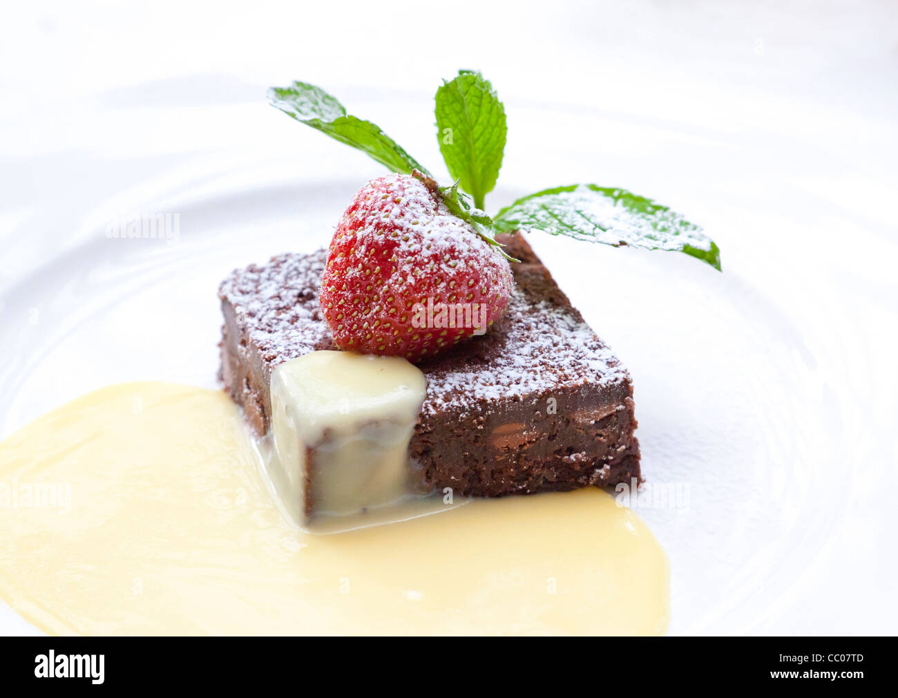 chocolate brownie slice with strawberry and served with custard Stock Photo