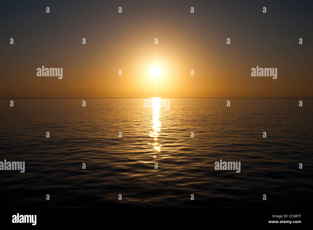 The sun approaches the horizon on a very clear and calm day over the water. Taken at Swains Reef on the southern end of the Great Barrier Reef of the coast of Queensland, Australia. Stock Photo