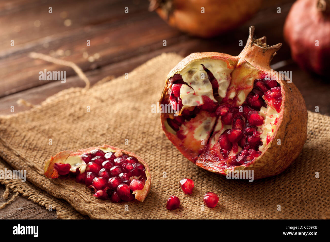 Pomegranate with Seeds on Jute and Wood Stock Photo