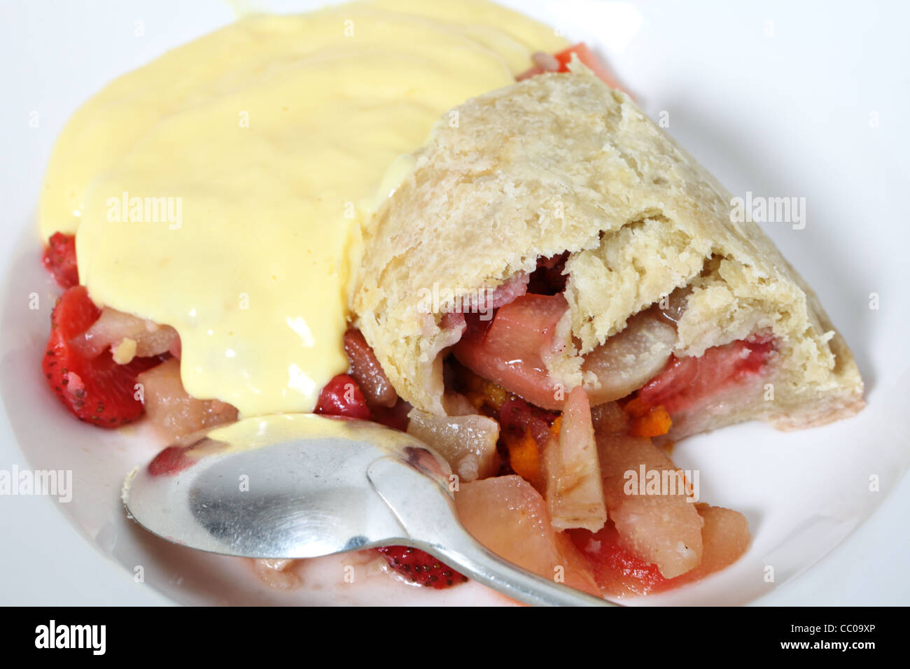 British steamed fruit pudding, of pears and strawberries with a sweet suet pastry crust, custard and an old-fashioned spoon Stock Photo