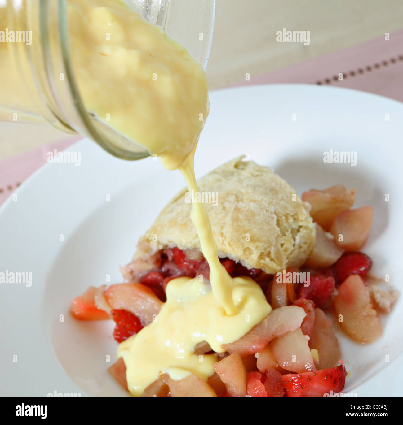 Custard being poured on a traditional British steamed fruit pudding, of